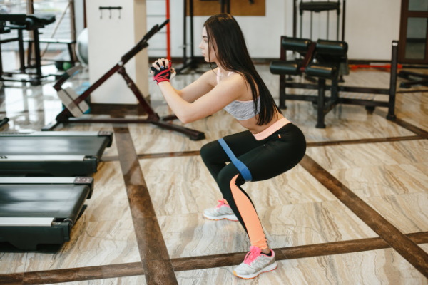 Exercices avec une bande élastique pour les jambes et les fesses à une femme assise sur une chaise, debout, couchée et autres