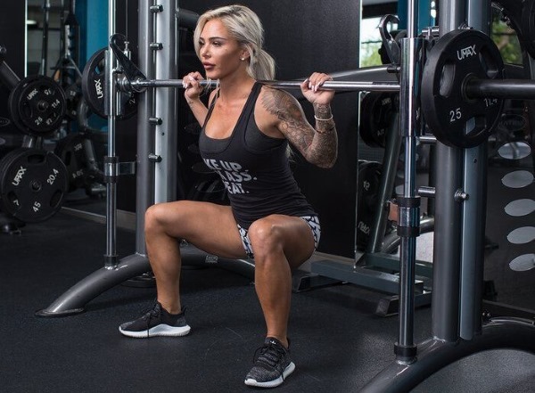 Smith squat pour les filles. Technique d'exécution sur les fesses, les genoux, une jambe, les quadriceps, frontale avec une position étroite et large