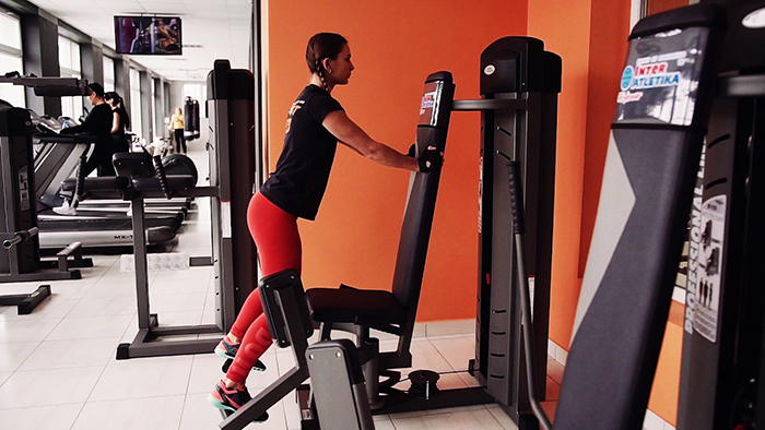 Élevage de jambes dans le simulateur assis, penché en avant, debout. Technique